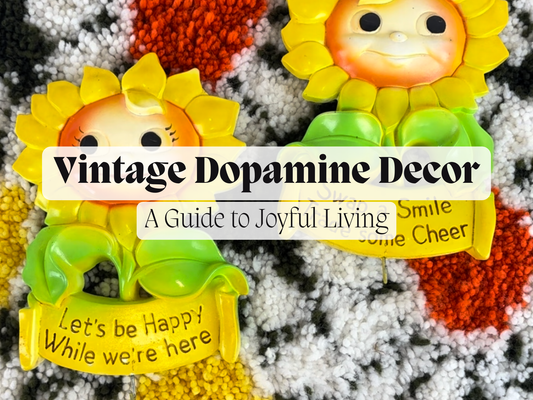 two anthropomorphic chalkware sunflowers with joyful messages sit on top of a 1970s latch hook rug. the title reads "Vintage Dopamine Decor A Guide to Joyful Living" a blog by The Cat Vintage in Crokett, CA